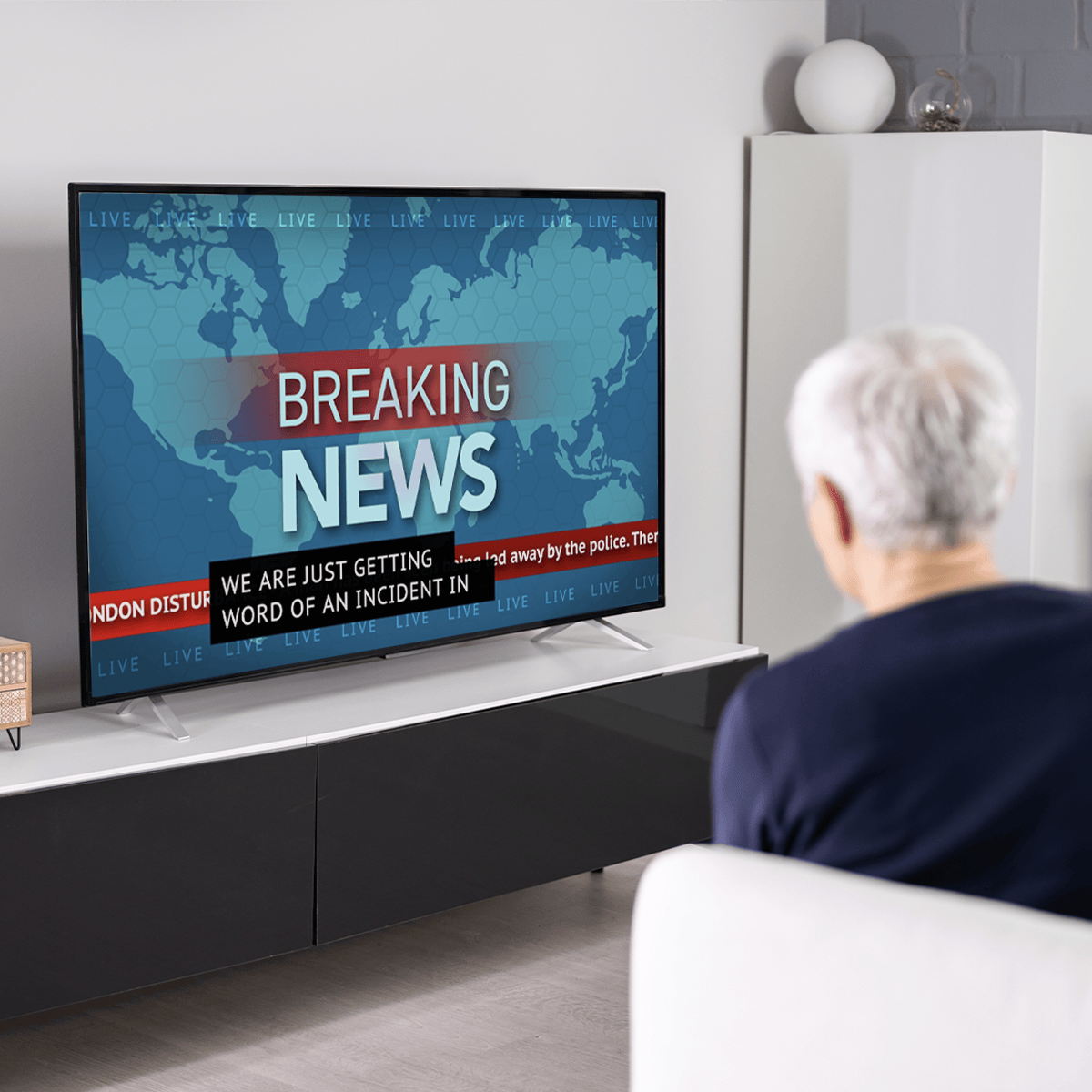 Senior man watching a television displaying breaking news