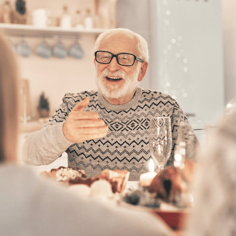Senior man smiling at the table with his family during a holiday dinner