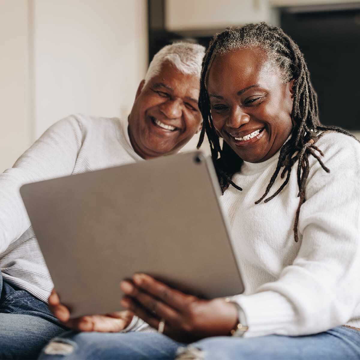Senior couple smiling while using a tablet