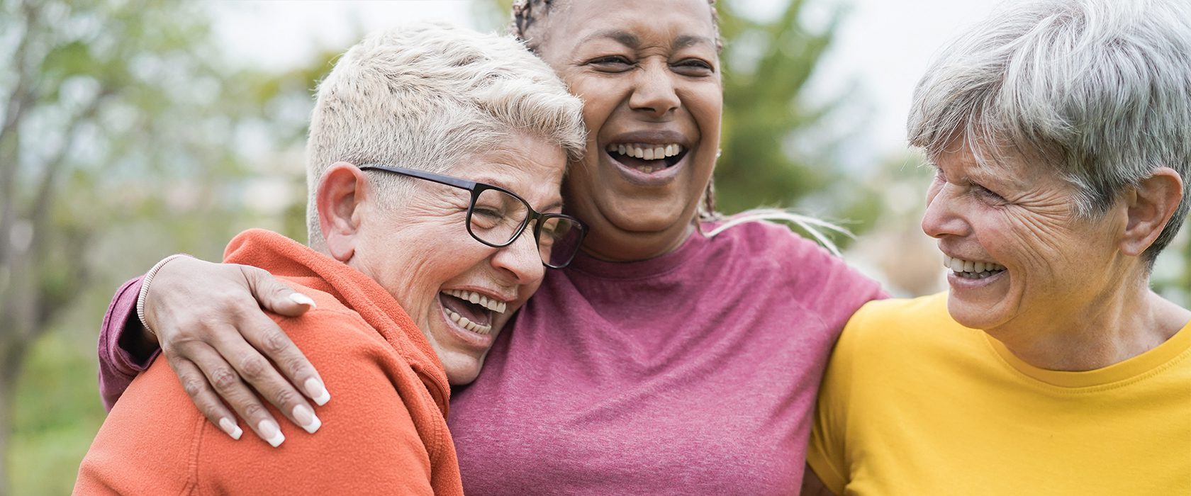 J2592_Friendship_1680x700 Two senior women laughing and hugging