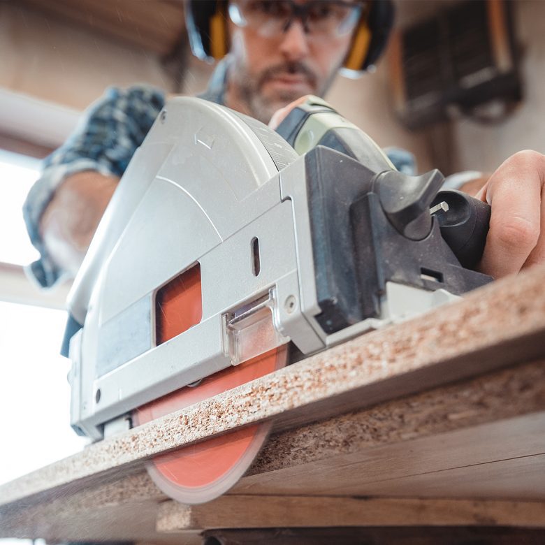 Man using a circular saw on a wood plank