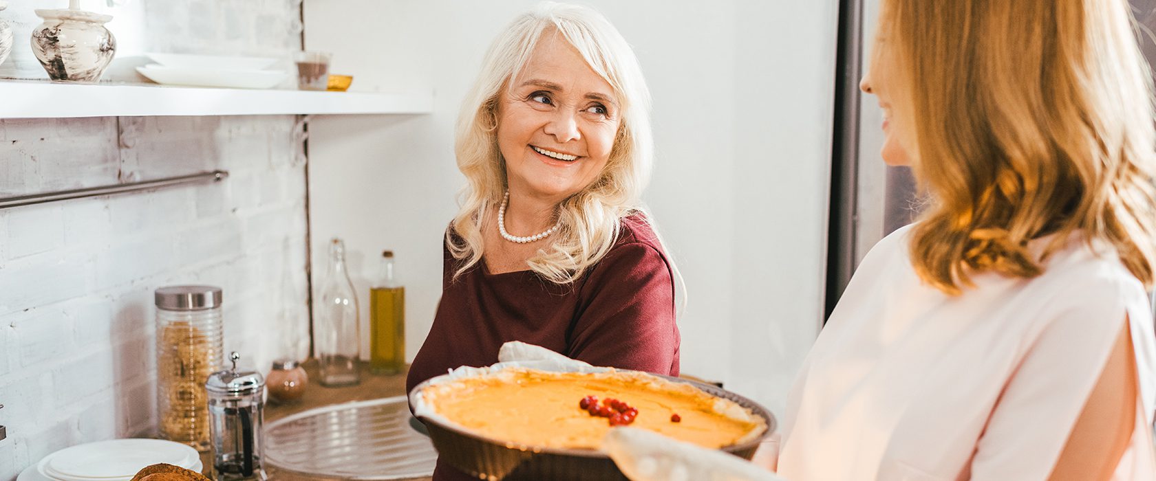 Senior mother and daughter cooking a pie together