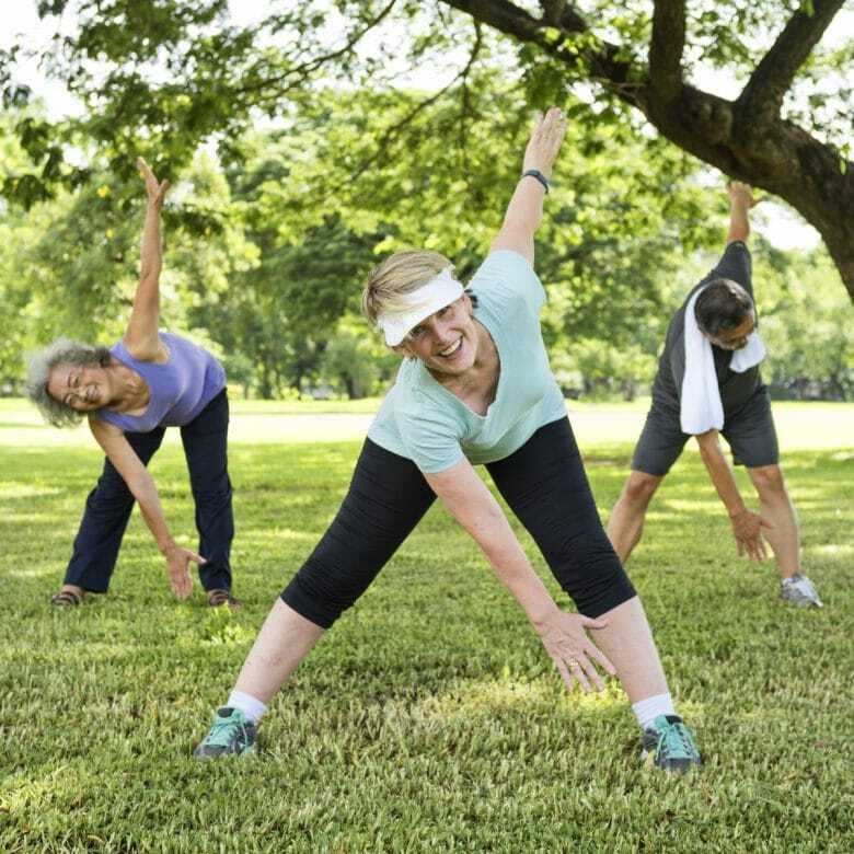 Two senior women and a man performing mobility exercises