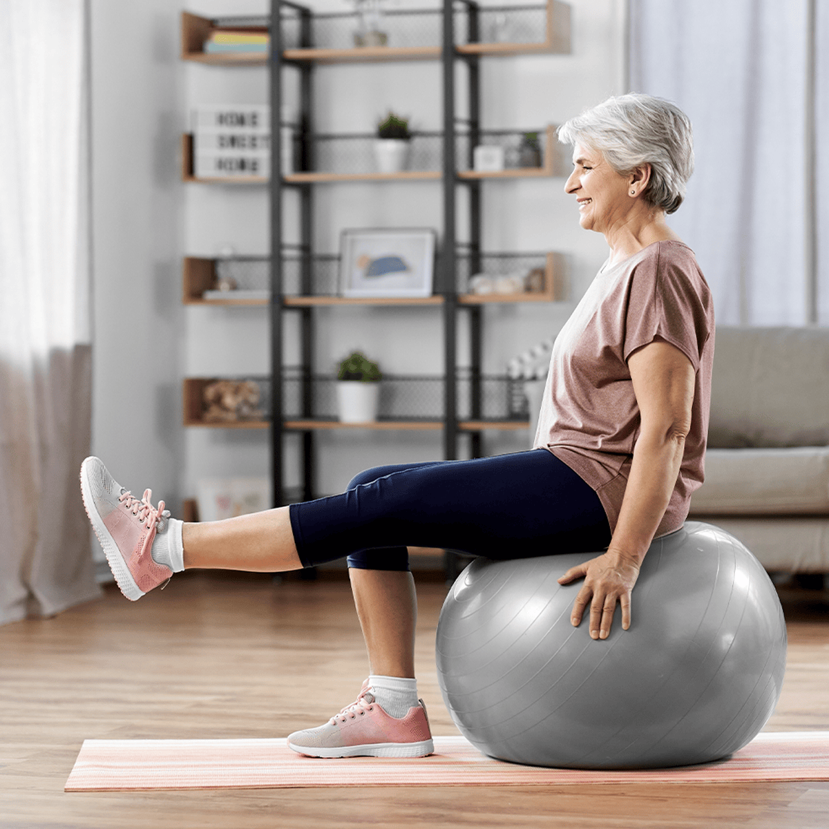 Senior woman performing mobility exercises in a yoga ball