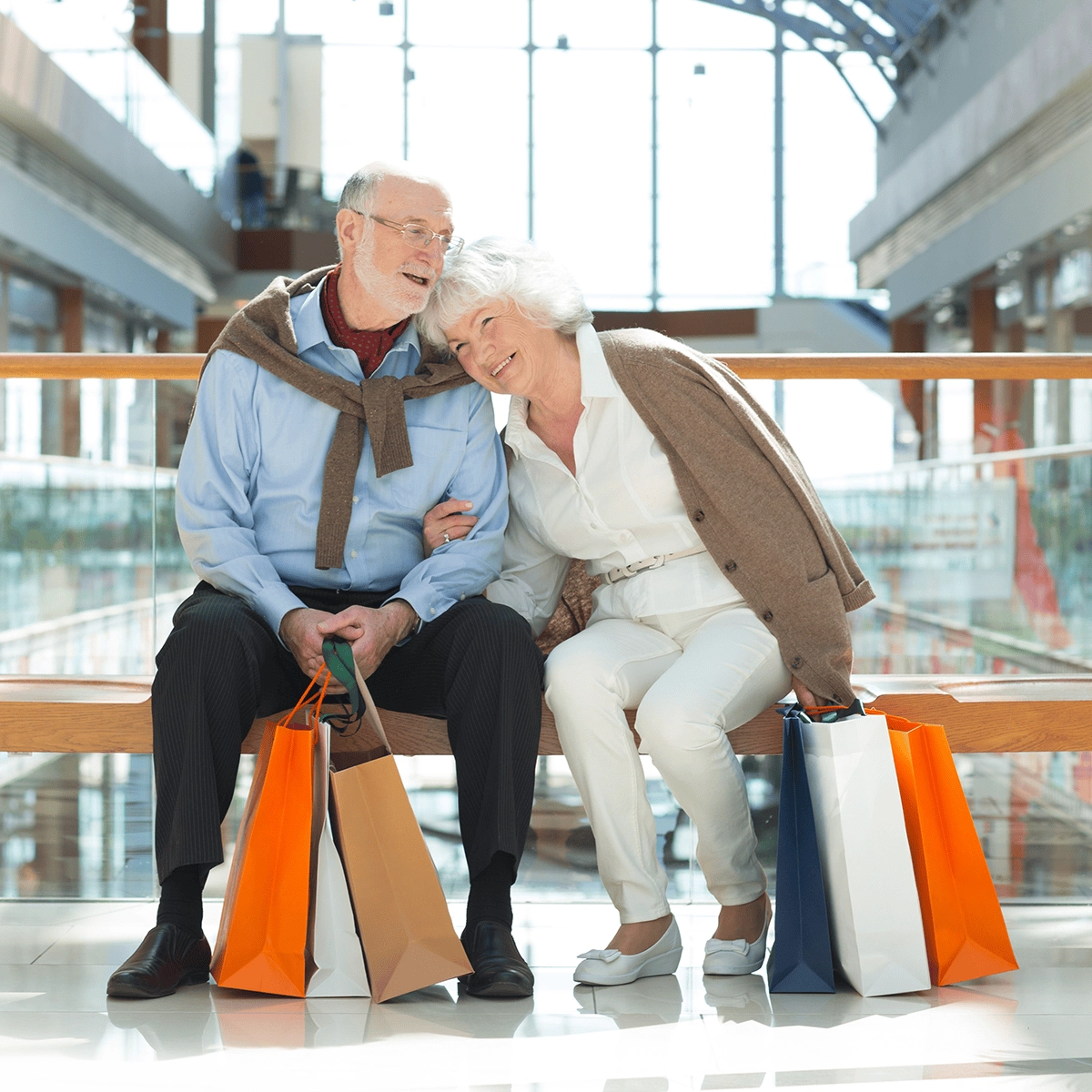 Two people sit on a bench, facing a serene lake with boats and mountains in the background, enjoying the peaceful scenery.