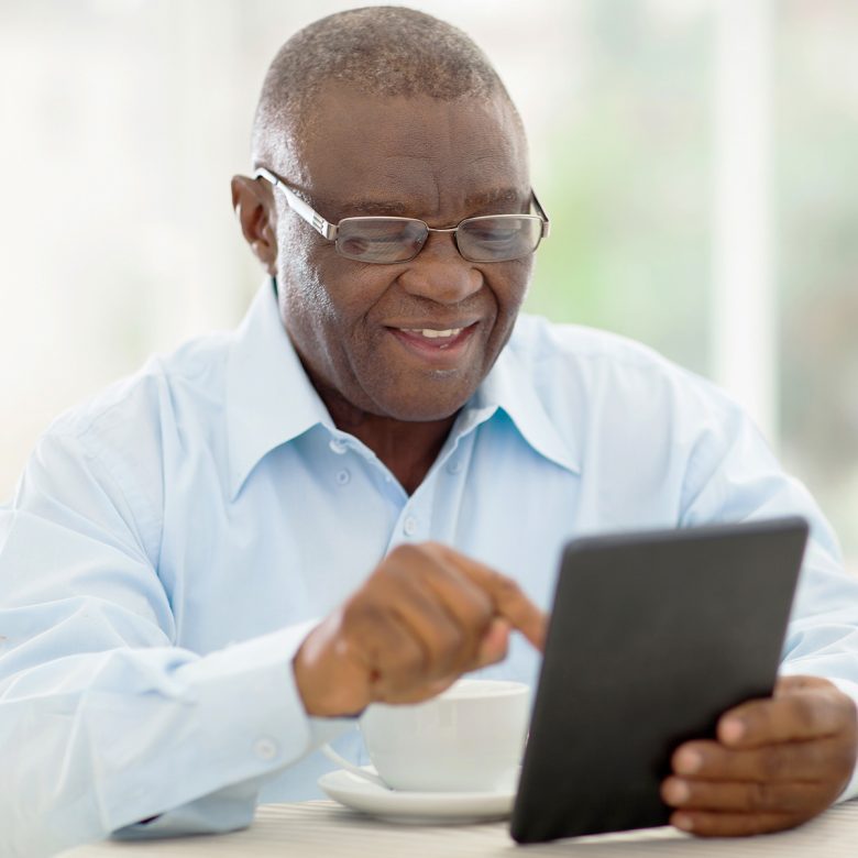 Senior man smiling while using a tablet