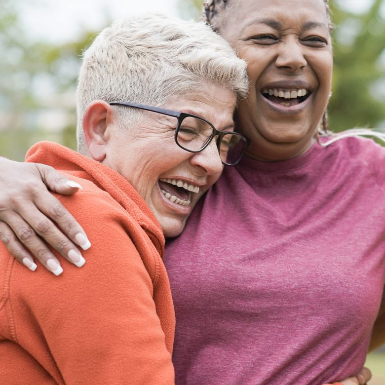 Two senior women laughing and hugging