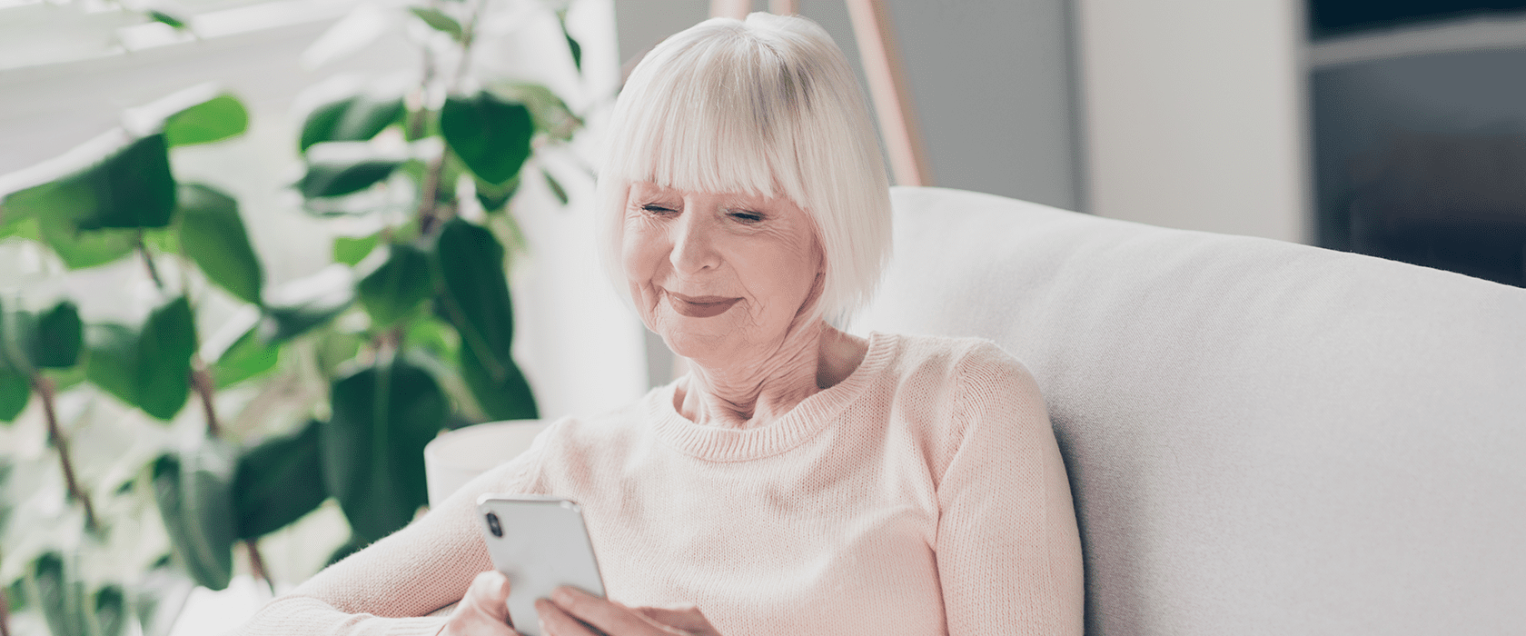 J2668_Blog_Stories-of-Connection_1680x700 Senior woman smiling while using a cell phone