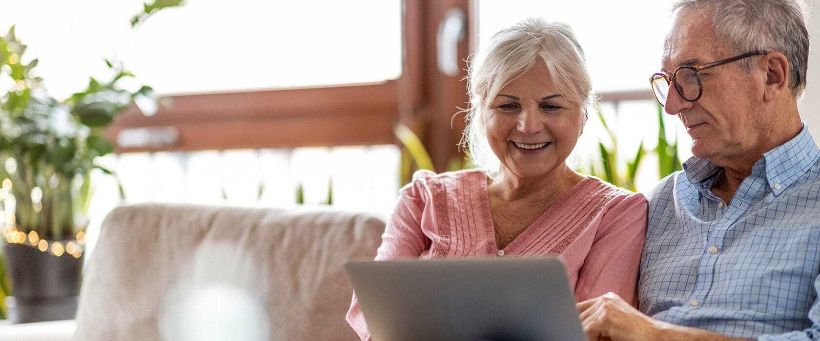 Senior couple smiliing while using a computer