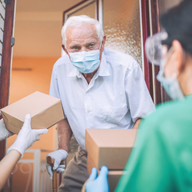 Senior man wearing a COVID face mask receiving a package at home