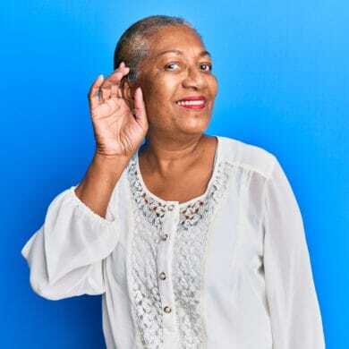 Smiling senior woman cupping her ear to listen better